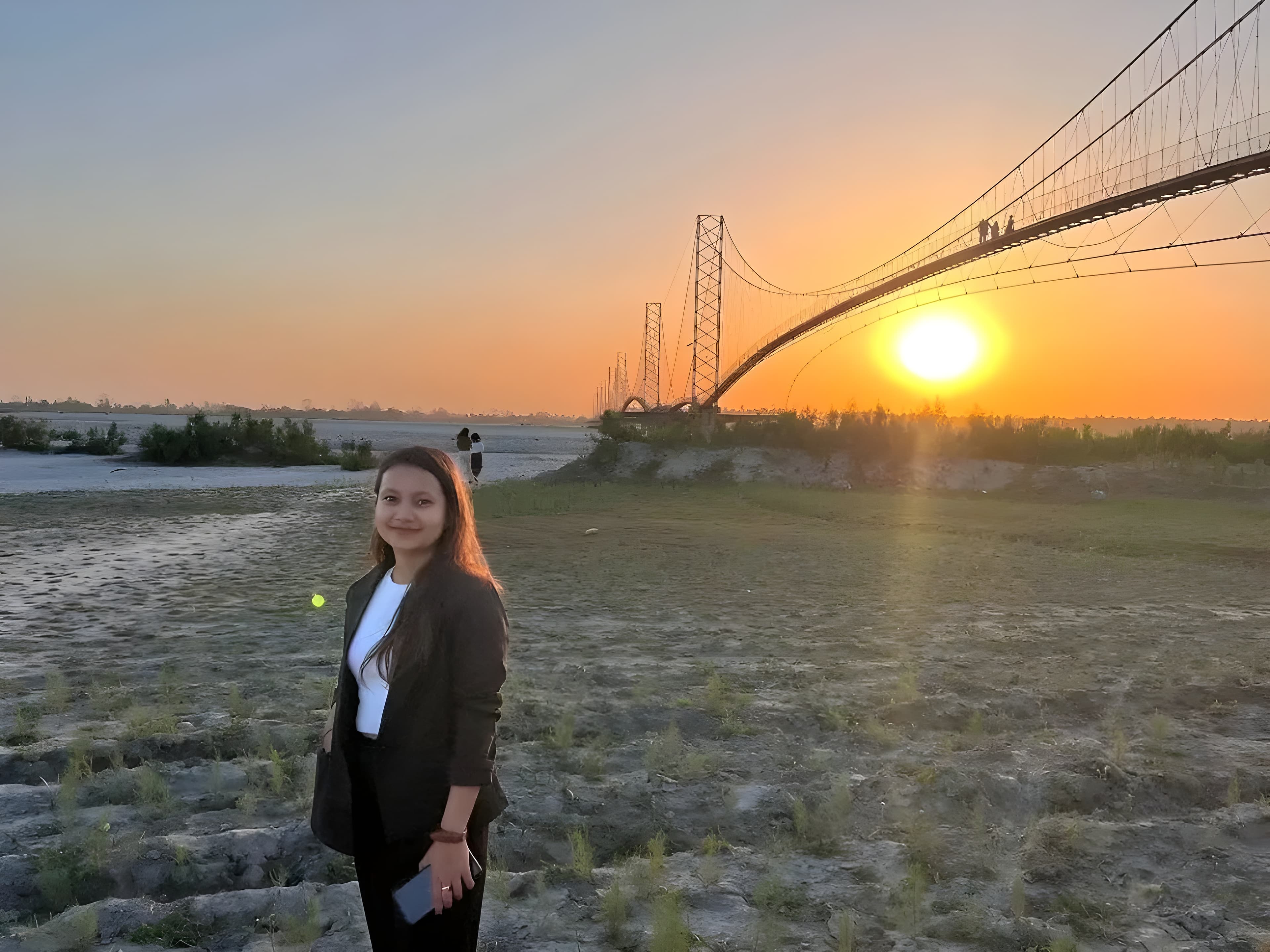 Somy Bhattarai standing near a bridge at sunset